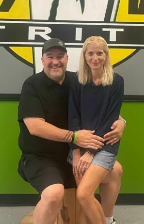 Mike and Paula Granam seated together in front of the club's green and yellow wall.