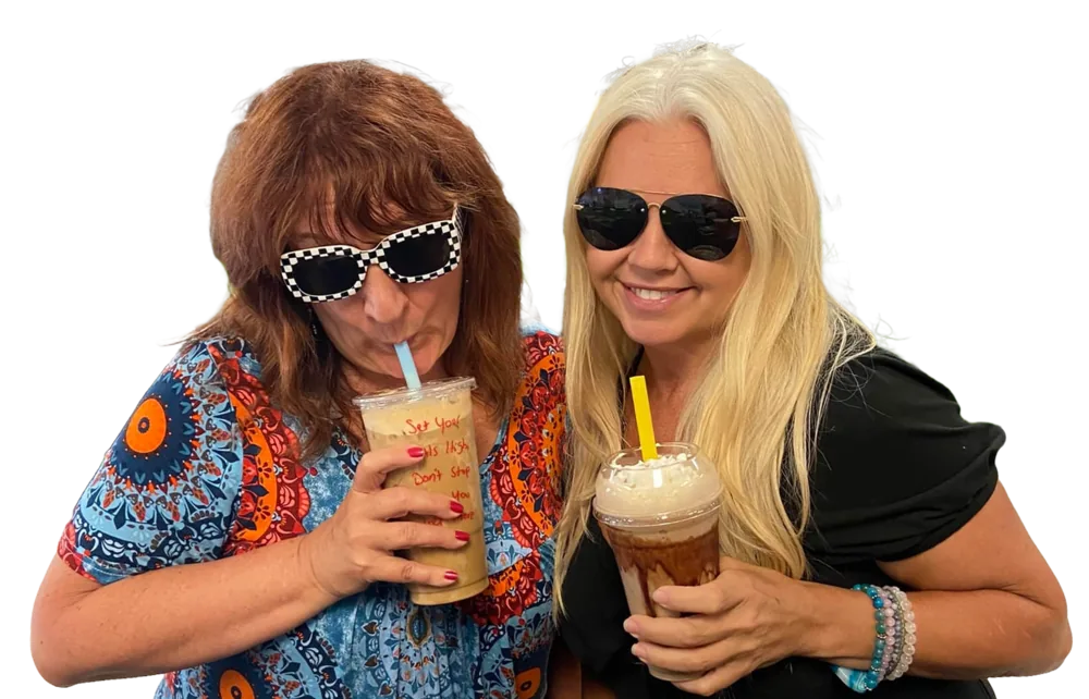 Two friends in sunglasses laugh together over their Good Vibes drinks.